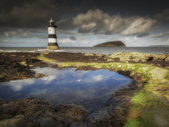 Lighthouse by sea against sky