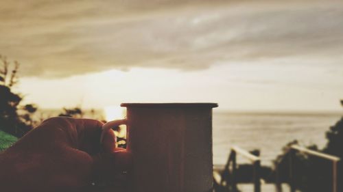 Close-up of hand holding smart phone against sea