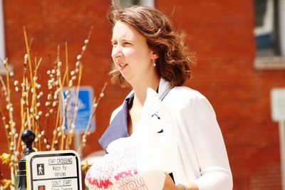 Woman standing against wall during sunny day