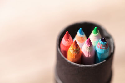 Close-up of colorful pencils in container on colored background