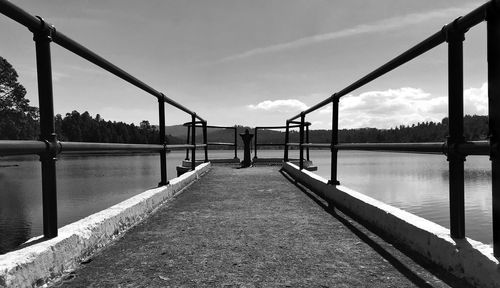 Footpath by lake against sky