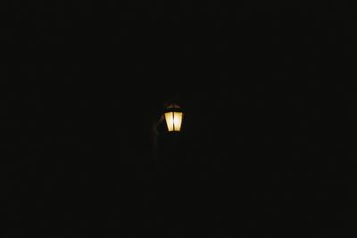 Low angle view of illuminated lamp against dark sky