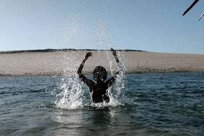 Man swimming in sea against clear sky