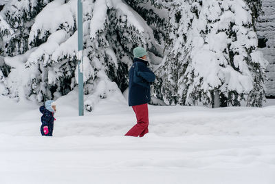 Mother and daughter walking in deep snow