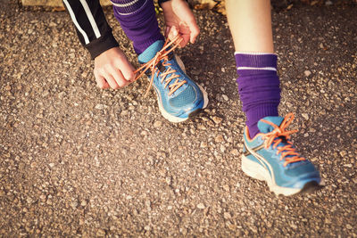 Low section of girl tying shoelace on footpath