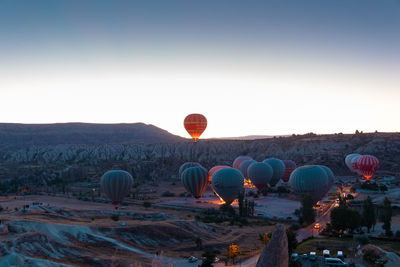 Hot air balloons on land against clear sky at sunset