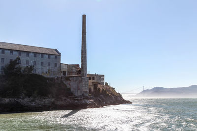 View of buildings by sea against clear sky