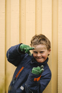 Portrait of smiling boy with disability making finger frame gesture against wall