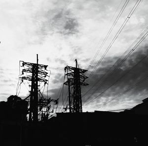 Low angle view of electricity pylon against cloudy sky