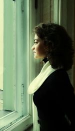 Thoughtful woman looking through window at home