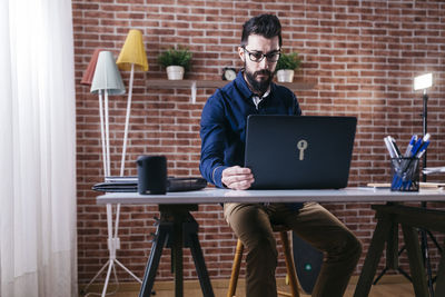 Full length of man using laptop on table in office