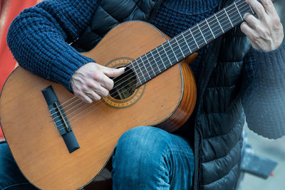 Midsection of man playing guitar