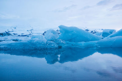 View of glacier in lake against cloudy sky