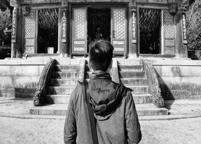 Rear view of man sitting on staircase of building