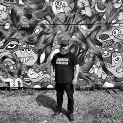 Full length of man standing against graffiti wall