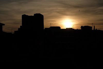 Silhouette buildings against sky during sunset