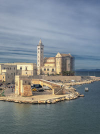 Buildings by sea against sky