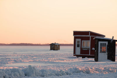 Built structure on snow field against clear sky during sunset