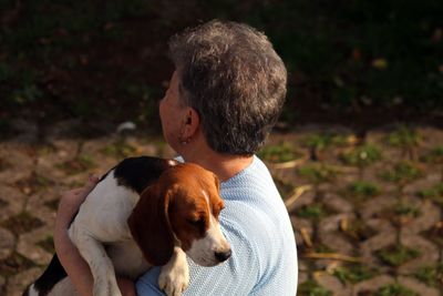 Close-up of woman carrying dog in sunny day