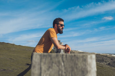 Side view of young man standing against wall