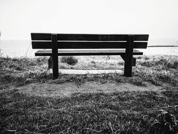 Empty bench on field against sky
