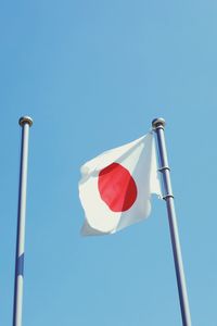 Low angle view of japanese flag against clear blue sky