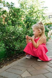 Portrait of young woman sitting on footpath