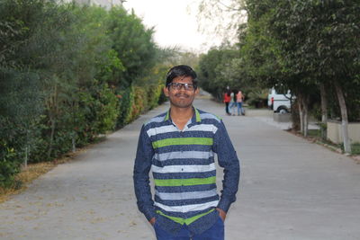 Portrait of young man standing by road