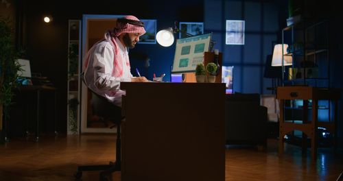 Rear view of man using digital tablet while standing in room