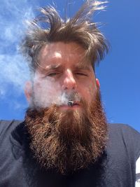 Portrait of man smoking against sky