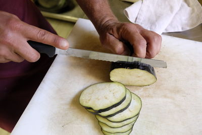 Midsection of man slicing eggplant on kitchen counter