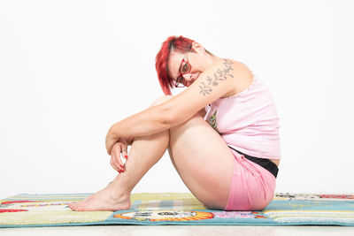 Portrait of young woman sitting against white background