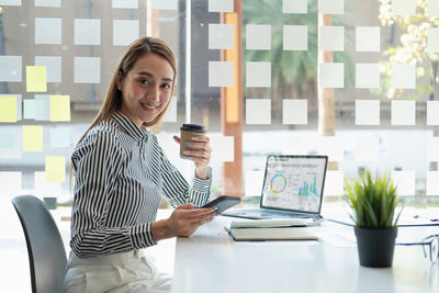 Portrait of woman using mobile phone while sitting on table