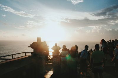 People on sea against sky during sunset