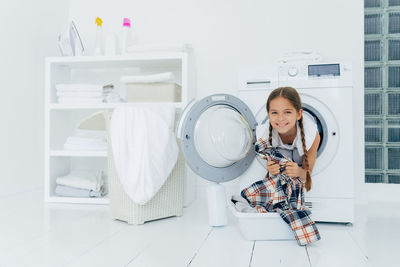 Portrait of smiling girl in washing machine at home