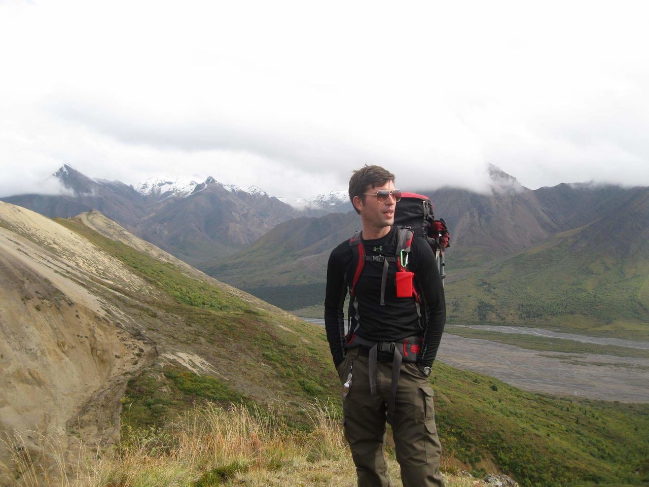 DISTANT VIEW OF MAN STANDING ON MOUNTAIN AGAINST SKY