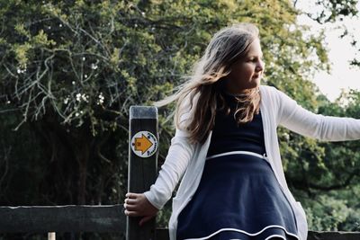 Young woman standing against tree