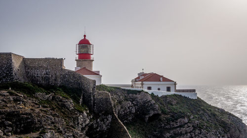 Lighthouse by sea against sky