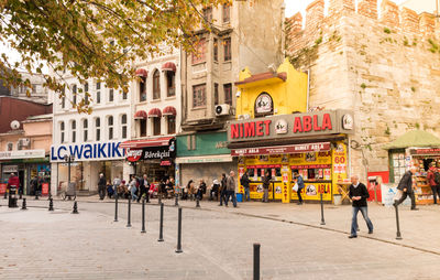 People on street against buildings in city