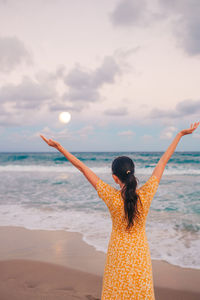 Rear view of woman standing at beach