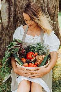 Young woman in rustic clothes holding basket of vegetables