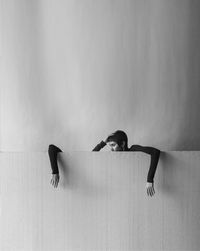 Woman looking at cropped hand hanging from wall