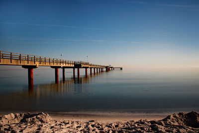 Pier over sea against sky during sunset