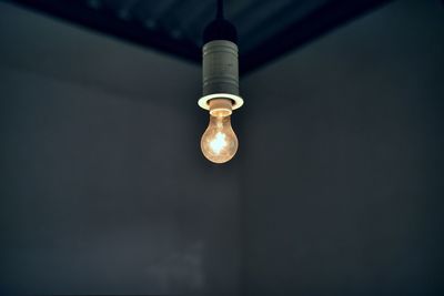 Illuminated light bulb hanging in room