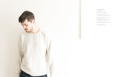 Young man standing against white wall