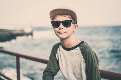 Portrait of man wearing sunglasses standing against sea