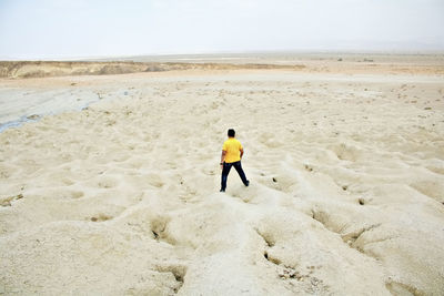 Rear view of man standing on sand at beach