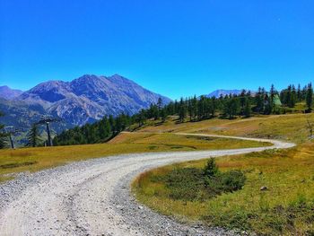 Road by mountains against clear blue sky