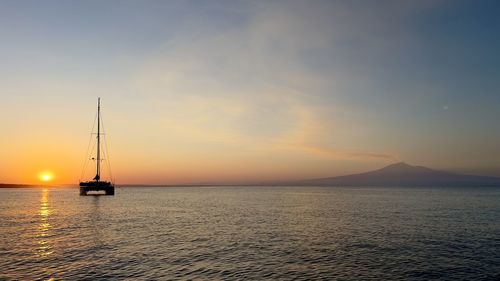 Sailboat sailing on sea against sky during sunset