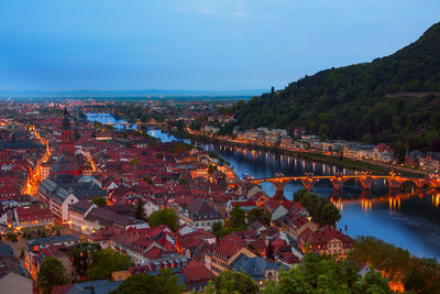 High angle view of illuminated buildings by river against sky